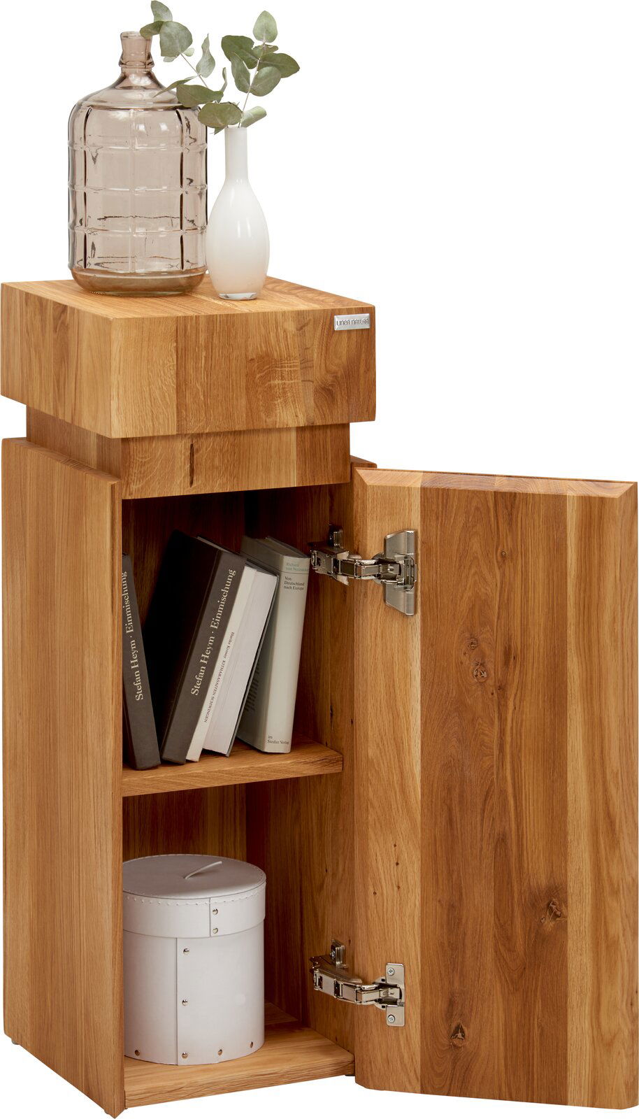 Beistelltisch aus Holz der Serie MAYA von Linea Natura, mit geöffneter Tür, Bücher und Dekoration darauf, aus seitlicher Perspektive.