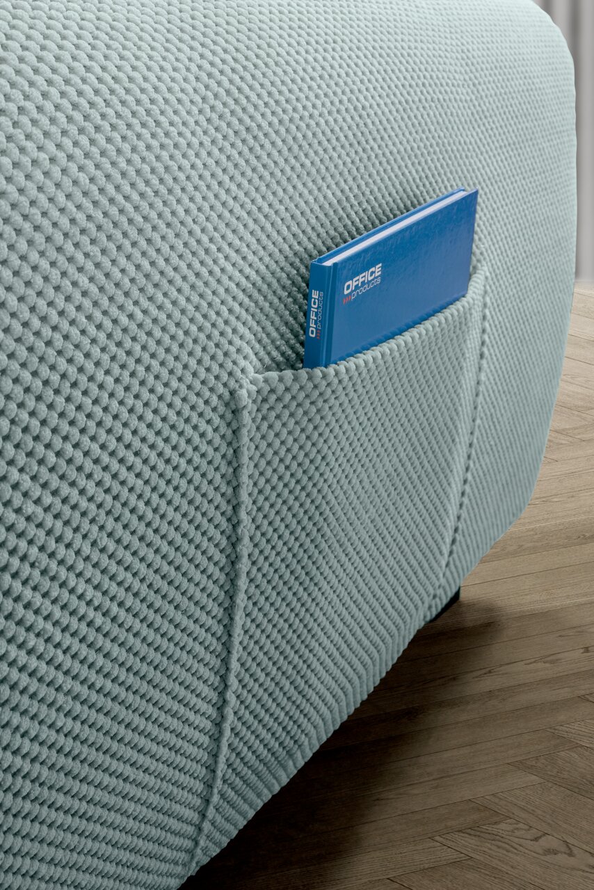 Nahaufnahme einer hellblauen Rundecke mit strukturierter Oberfläche und einer Tasche, in der ein blaues Buch steckt. Perspektive von der Seite.