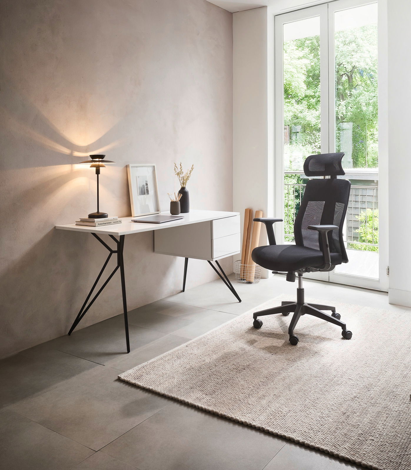 Moderner Drehstuhl in einem hellen Raum, seitliche Perspektive, neben einem Schreibtisch mit Lampe und Dekoration.