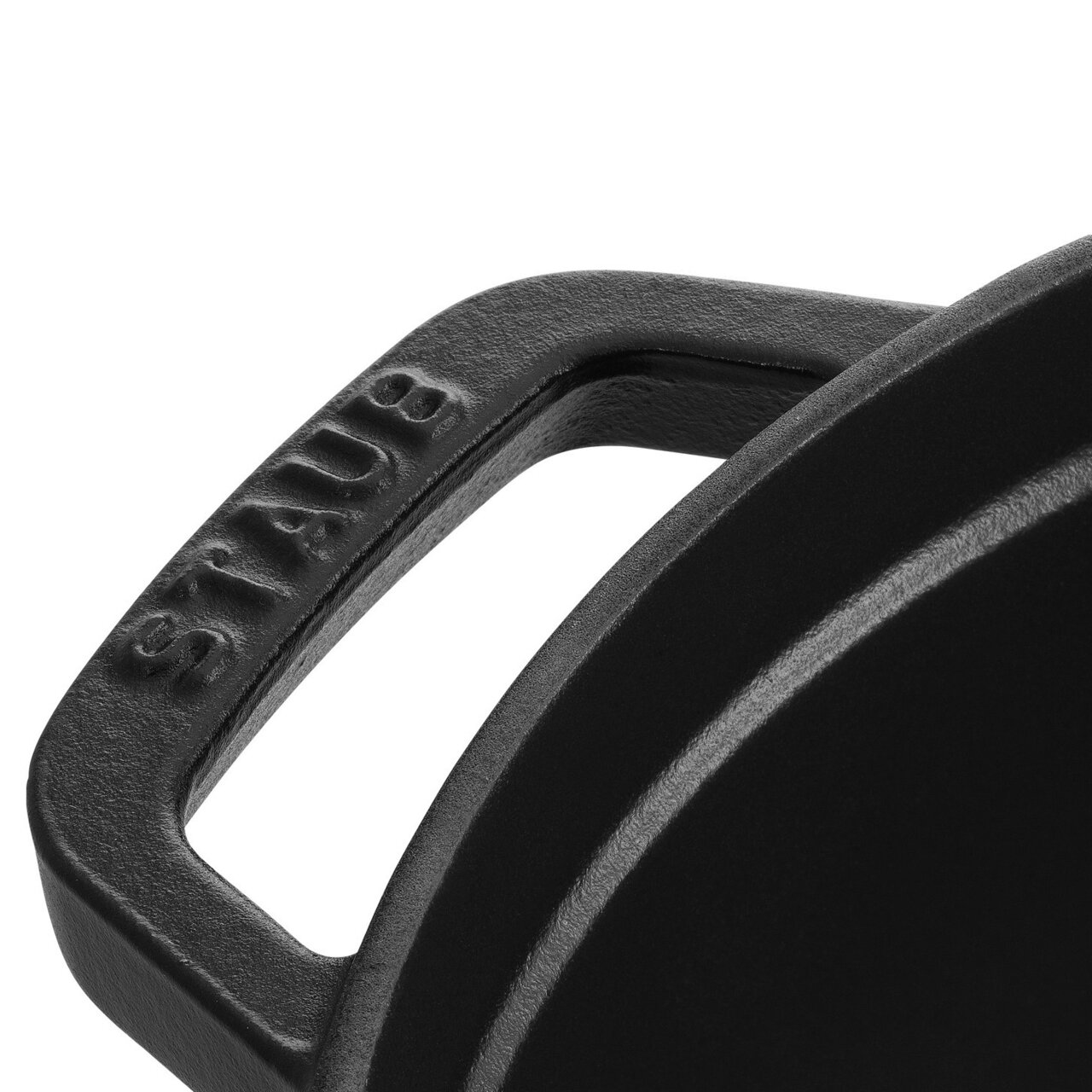 Close-up van een zwarte handgreep van een ronde braadpan met het opschrift 'STAUB'.
