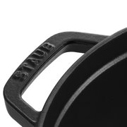 Close-up van een zwarte handgreep van een ronde braadpan met het opschrift 'STAUB'.