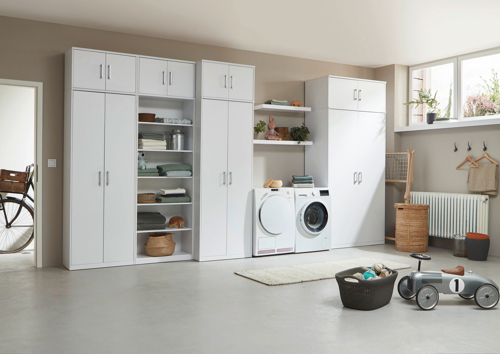 Moderne weiße Schrankwand mit Regalen und Aufbewahrungsmöglichkeiten in einem hellen Raum, seitliche Perspektive