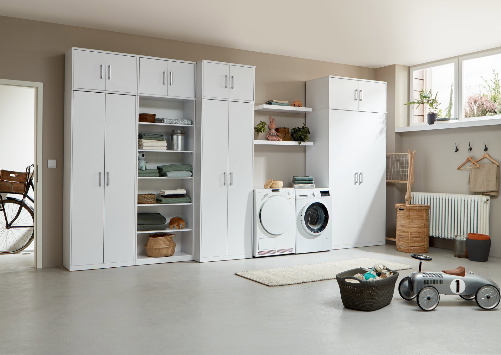 Moderne weiße Schrankwand mit Regalen und Aufbewahrungsmöglichkeiten in einem hellen Raum, seitliche Perspektive