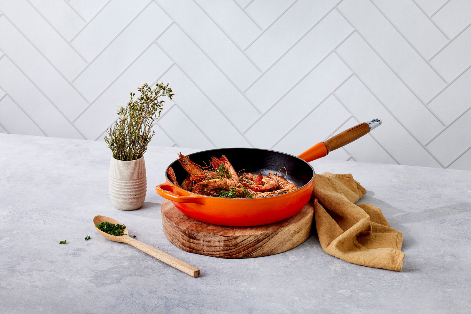 Sautepfanne 28cm in Ofenrot mit Holzgriff, gefüllt mit Garnelen, auf einem Holzbrett, seitliche Perspektive.