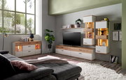 Wohnzimmer mit moderner Möbelkombination, bestehend aus Sideboard, TV-Lowboard und Hängeschränken in Holz- und Weißtönen, mit dekorativer Beleuchtung und Pflanzen, seitliche Perspektive.