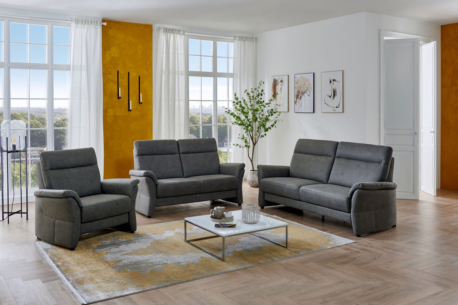 Modernes Wohnzimmer mit grauer Polstergarnitur (Sessel, 2-Sitzer und 3-Sitzer) auf Teppich und Couchtisch, fotografiert in frontaler leicht seitlicher Perspektive.