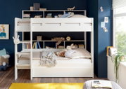 Wit stapelbed met ingebouwde planken, versierd met boeken en speelgoed, in een kinderkamer met een blauwe muur. Vooraanzicht.