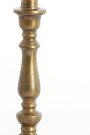 Nahaufnahme eines antik wirkenden, goldfarbenen Lampenfußes mit dekorativen Verzierungen.