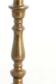 Nahaufnahme eines antik wirkenden, goldfarbenen Lampenfußes mit dekorativen Verzierungen.