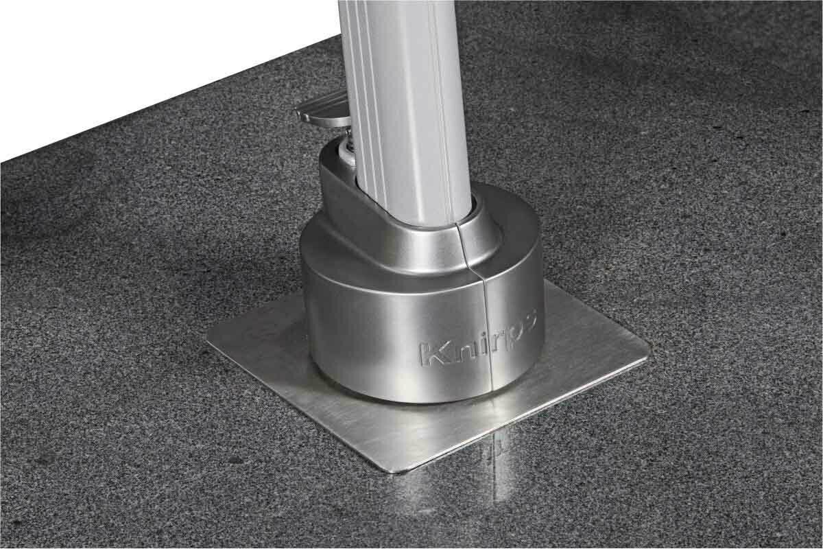 Nahaufnahme des Sockels eines Pendelschirms mit silbernem Metallfuß auf grauem Boden.