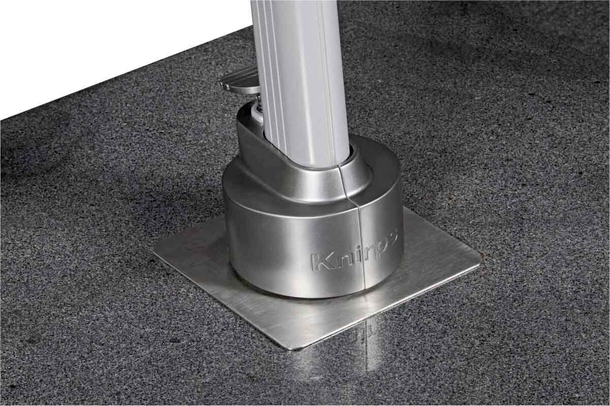 Nahaufnahme des Sockels eines Pendelschirms mit silbernem Metallfuß auf grauem Boden.