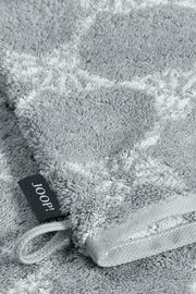 Nahaufnahme eines grauen Waschhandschuhs mit einem dezenten Muster und einer Schlaufe, perspektivisch von oben fotografiert.