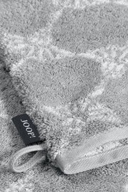 Nahaufnahme eines grauen Waschhandschuhs mit einem dezenten Muster und einer Schlaufe, perspektivisch von oben fotografiert.