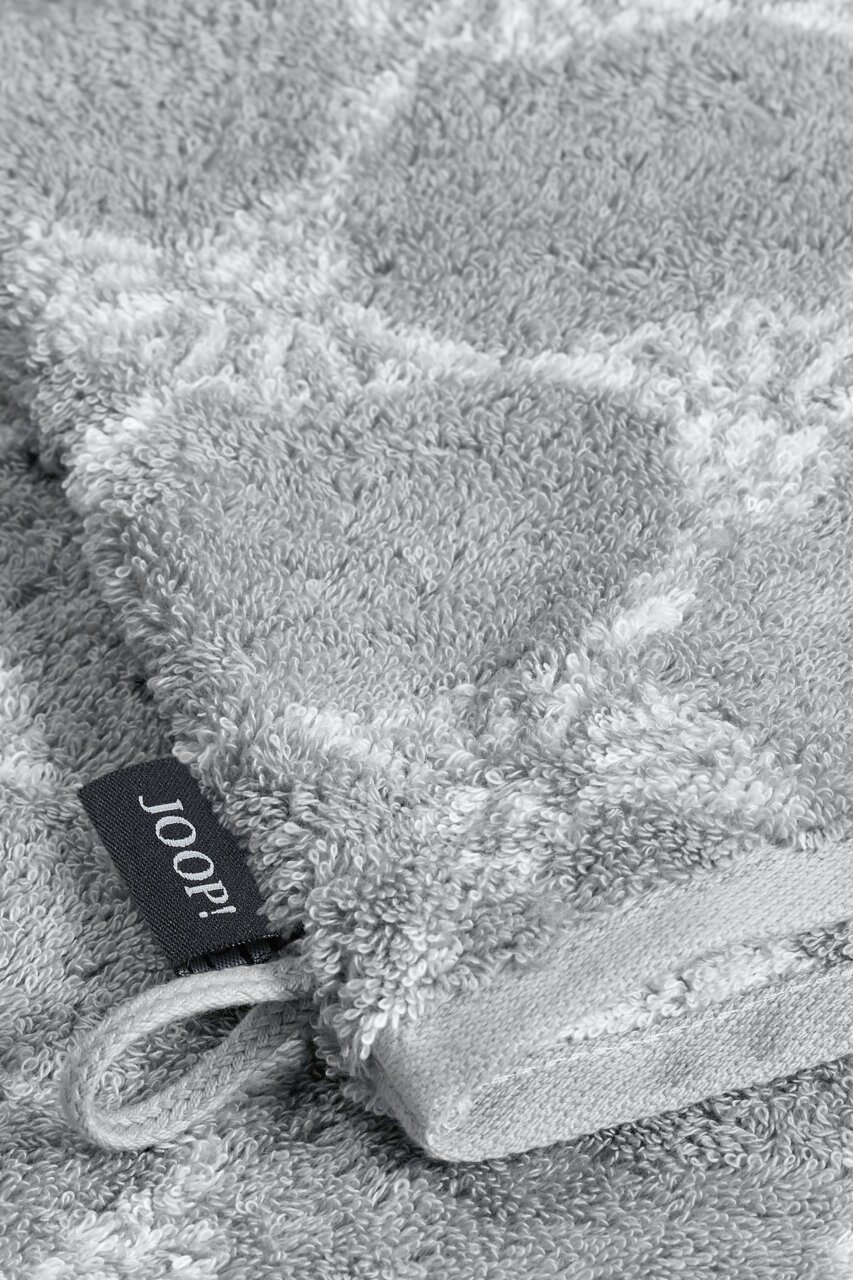 JOOP! Waschhandschuh CORNFLOWER CLASSIC Nahaufnahme eines grauen Waschhandschuhs mit einem dezenten Muster und einer Schlaufe, perspektivisch von oben fotografiert.