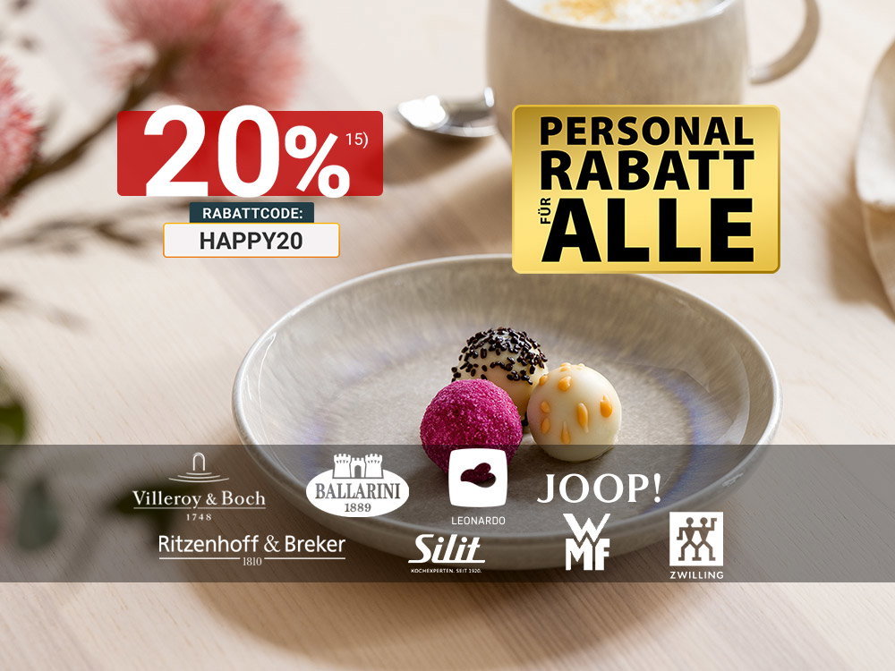 Drei bunte Pralinen auf einem eleganten Keramikteller, dazu eine Tasse Cappuccino.