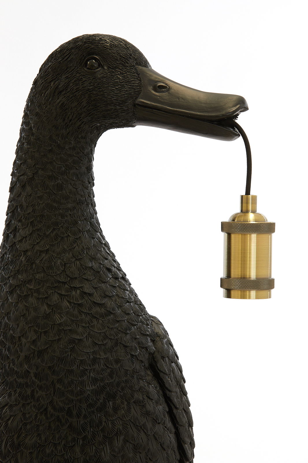 Nahaufnahme einer Tischleuchte in Form einer schwarzen Ente, die eine goldene Lampenfassung im Schnabel hält.