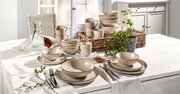 Kombiservice 30-teilig in beige mit elegantem Muster, arrangiert auf einem gedeckten Tisch in heller, einladender Umgebung. Perspektive von vorne.