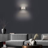 Moderne Wandleuchte PURE Clipse in einem stilvollen Wohnzimmer, frontal an der Wand montiert, mit sanftem Lichtschein nach oben und unten.