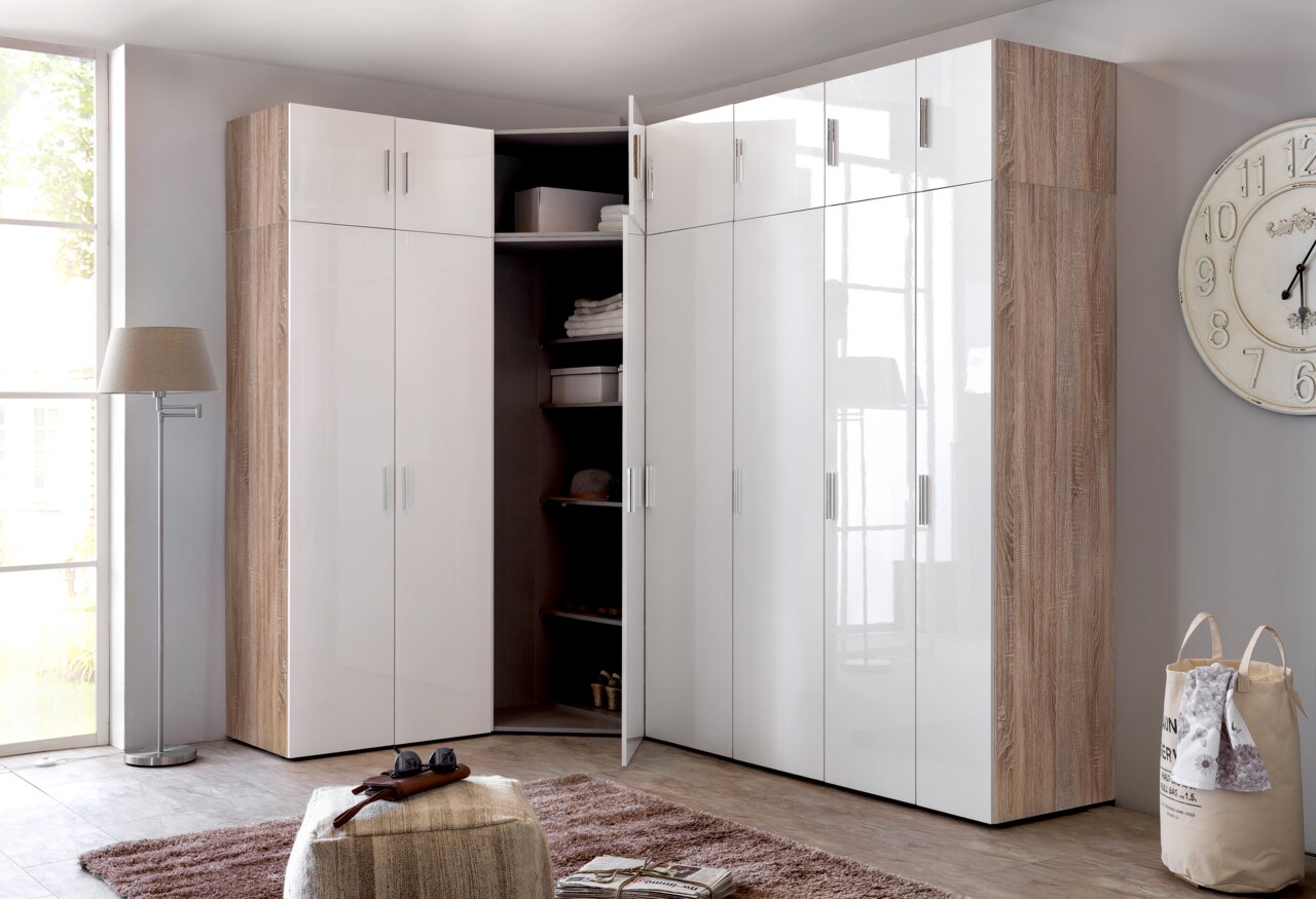 Eckkleiderschrank in moderner Perspektive mit weißen Hochglanztüren und Holzdekor, teilweise geöffnet, zeigt Innenregale mit Kleidung und Accessoires.