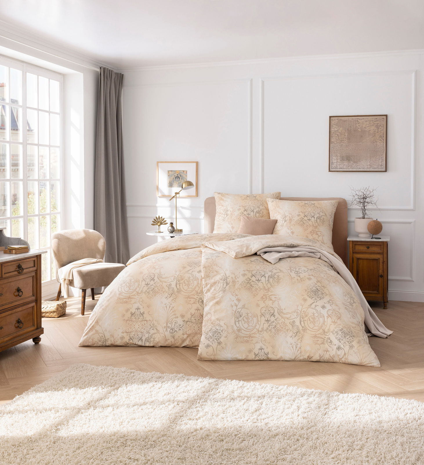 Elegante Bettwäsche in einem hellen, gemusterten Design auf einem Doppelbett in einem stilvoll eingerichteten Schlafzimmer mit Tageslicht von der linken Seite.