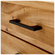 Nahaufnahme eines Schreibtischs aus Holz mit einer schwarzen Griffleiste, seitliche Perspektive