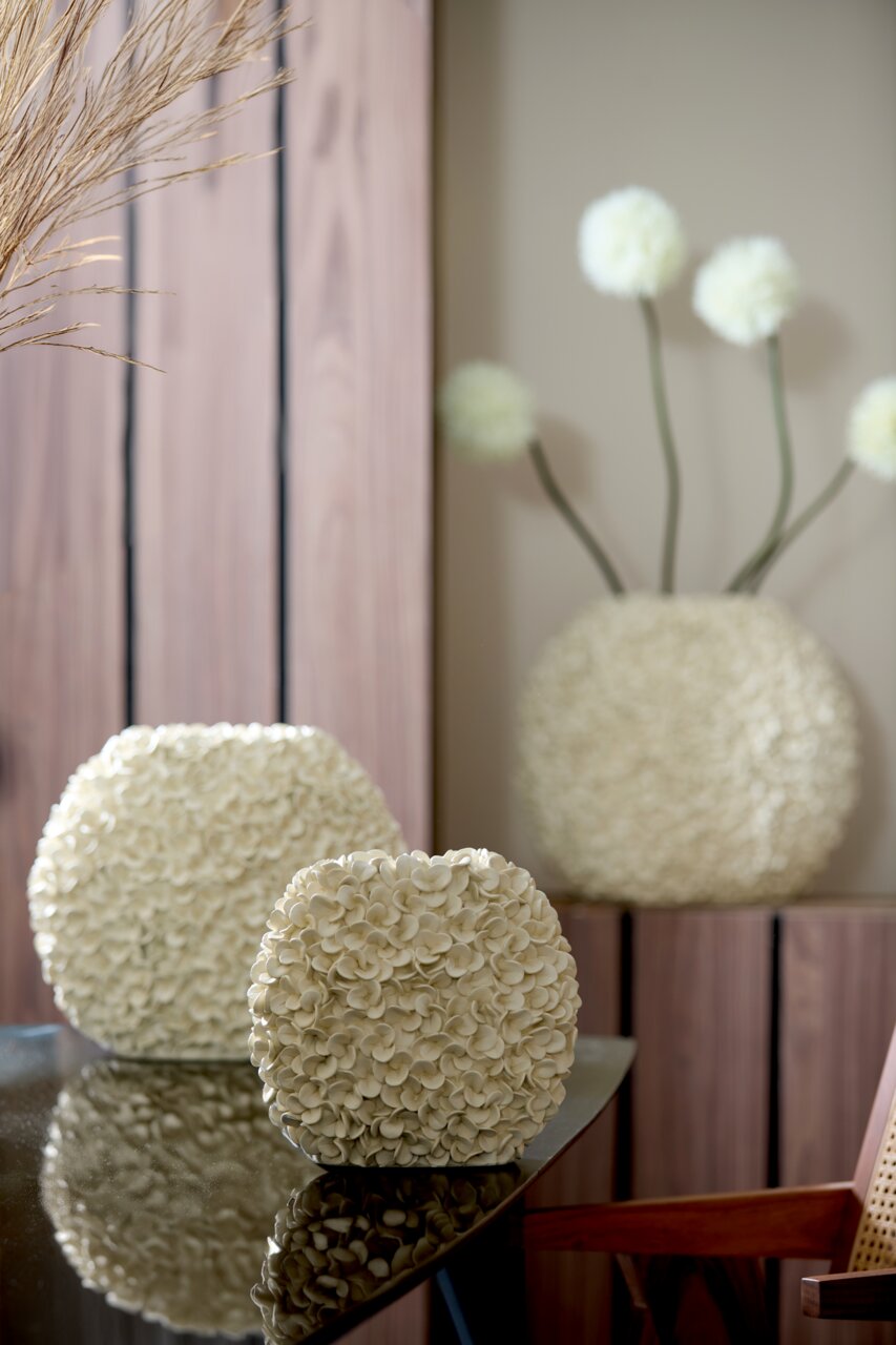 Light&Living Vase PHYLIA Nahaufnahme einer dekorativen Vase mit blütenförmiger Struktur auf einem Tisch, im Hintergrund weitere Vasen und Dekorationen.