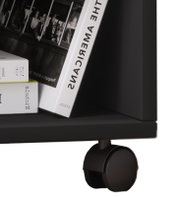 Detailansicht aus seitlicher Perspektive: schwarzer Servierwagen/Beistelltisch mit Ablage, darauf Bücher und eine kleine Box, unten eine große schwarze Lenkrolle