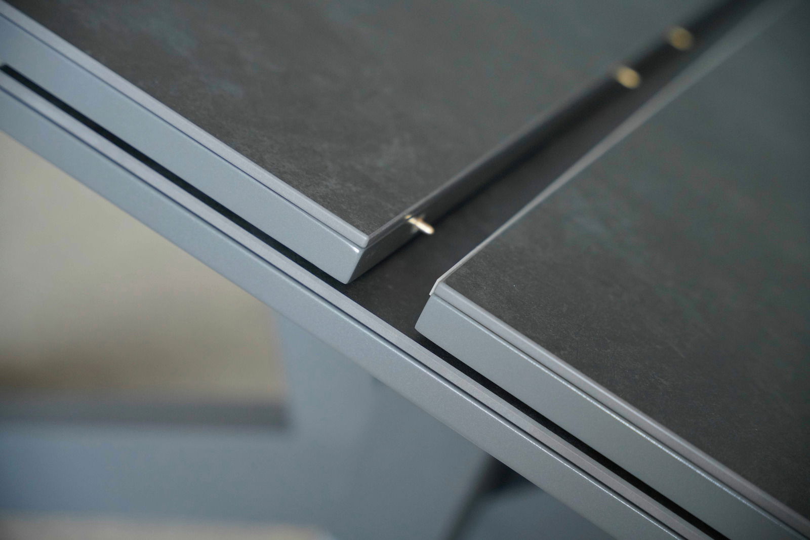 Nahaufnahme eines modernen Esstisches mit grauer Tischplatte und Metallrahmen, aus der Vogelperspektive fotografiert.