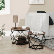 Wohnzimmer-Szene mit zwei runden Beistelltischen aus dunkler Holzoptik und schwarzem Metallgestell neben einem hellen Sofa, fotografiert in seitlicher Perspektive leicht von vorne; auf den Tischen stehen Lampe, Tasse und Magazin.