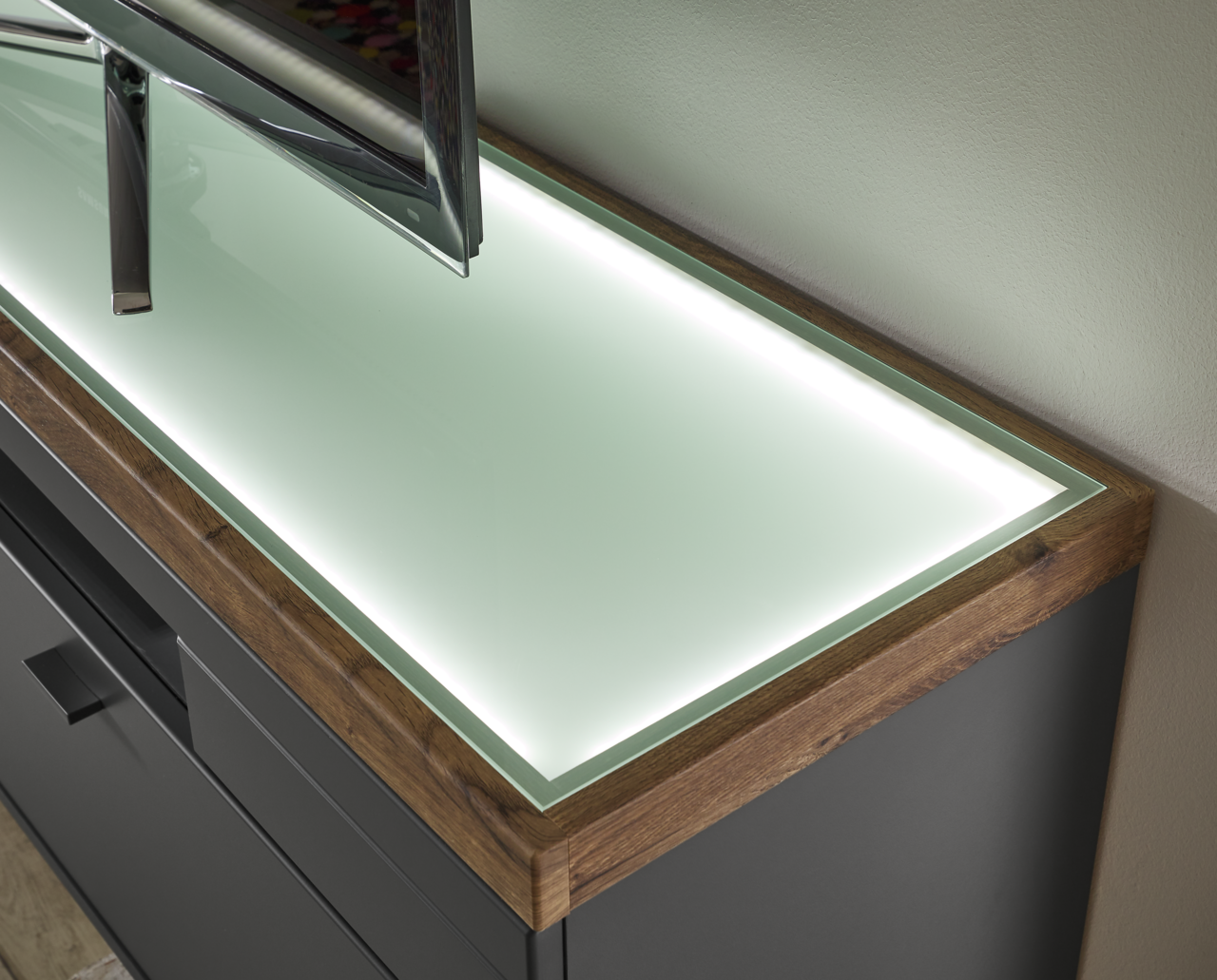 TV-Lowboard mit Glasoberfläche und Holzrahmen, seitliche Perspektive