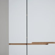 Nahaufnahme eines modernen weißen Garderobenschranks mit Holzgriffen, Frontalansicht