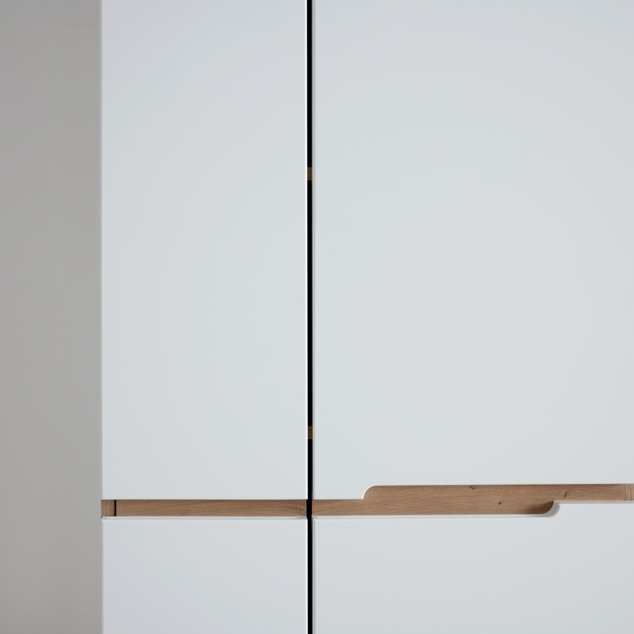 Nahaufnahme eines modernen weißen Garderobenschranks mit Holzgriffen, Frontalansicht