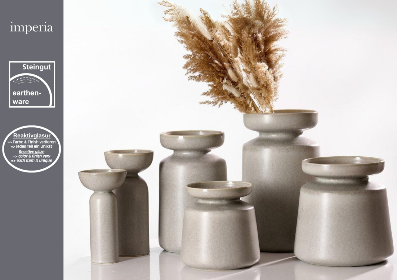 Sechs graue Vasen der Serie Imperia aus Steingut mit Reaktivglasur, in verschiedenen Größen, von vorne betrachtet. Eine Vase ist mit getrockneten Gräsern dekoriert.
