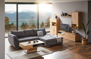 Gemütliche Wohnzimmer-Ecke mit grauem Ecksofa und Holzmöbeln, Blick auf Berge und See durch große Fenster.