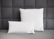 Zwei weiße Spessarttraum 3-Kammerkissen auf einem grauen Bett, frontal fotografiert vor einer gepolsterten Wand.
