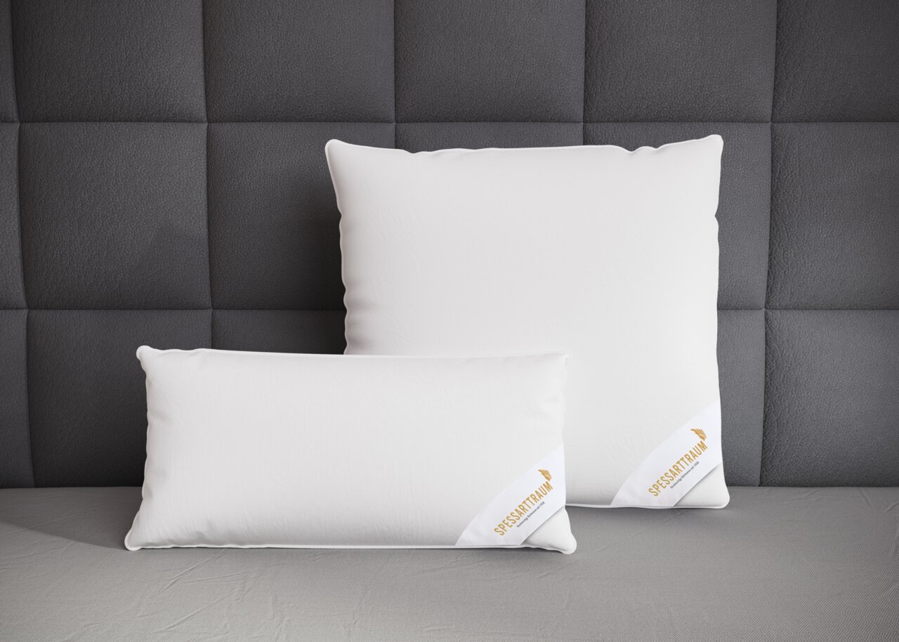 Twee witte Spessarttraum-kussens met drie kamers op een grijs bed, van voren gefotografeerd tegen een gestoffeerde wand.