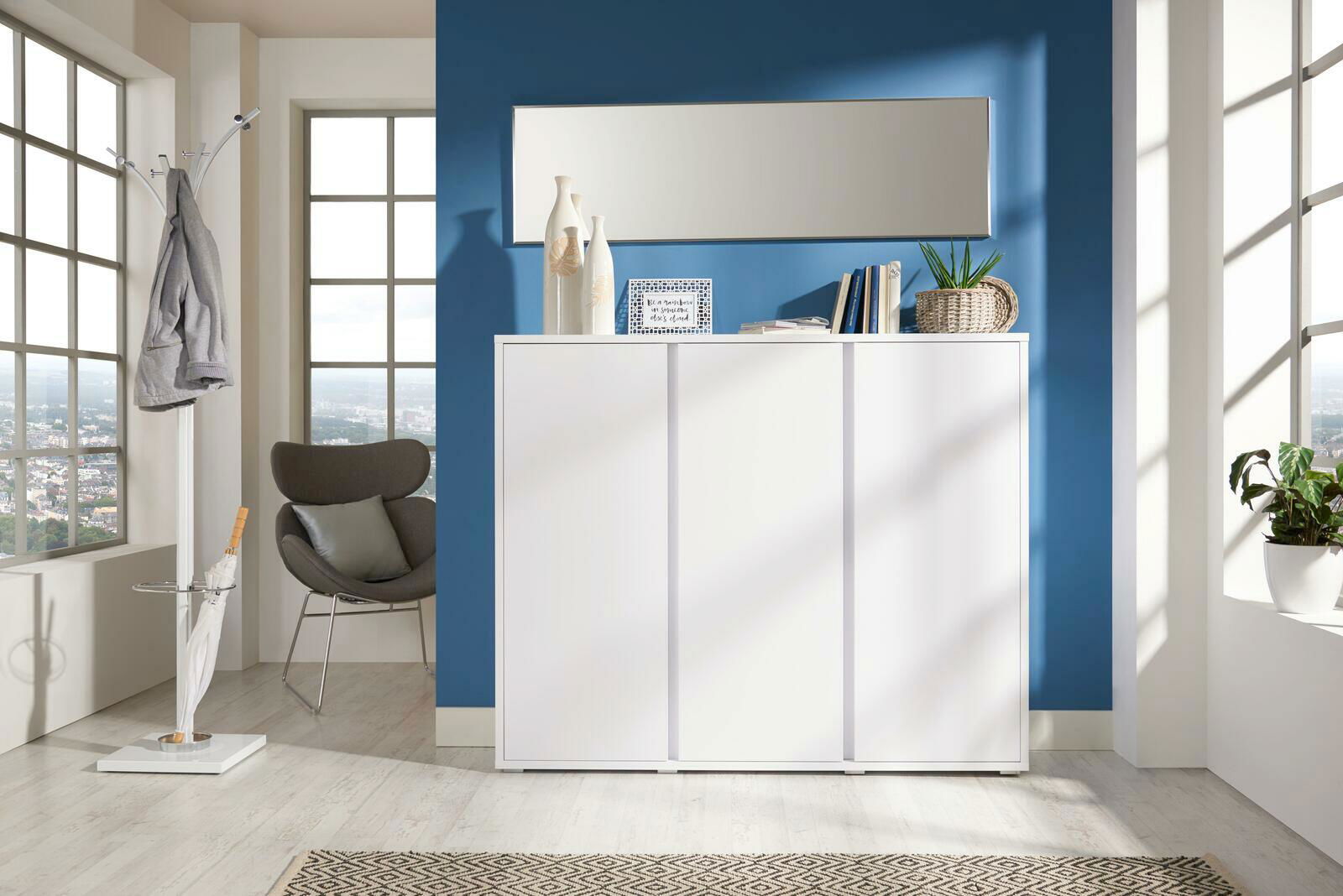 Moderner weißer Schuhschrank in einem hellen Raum mit blauer Wand, von vorne gesehen.