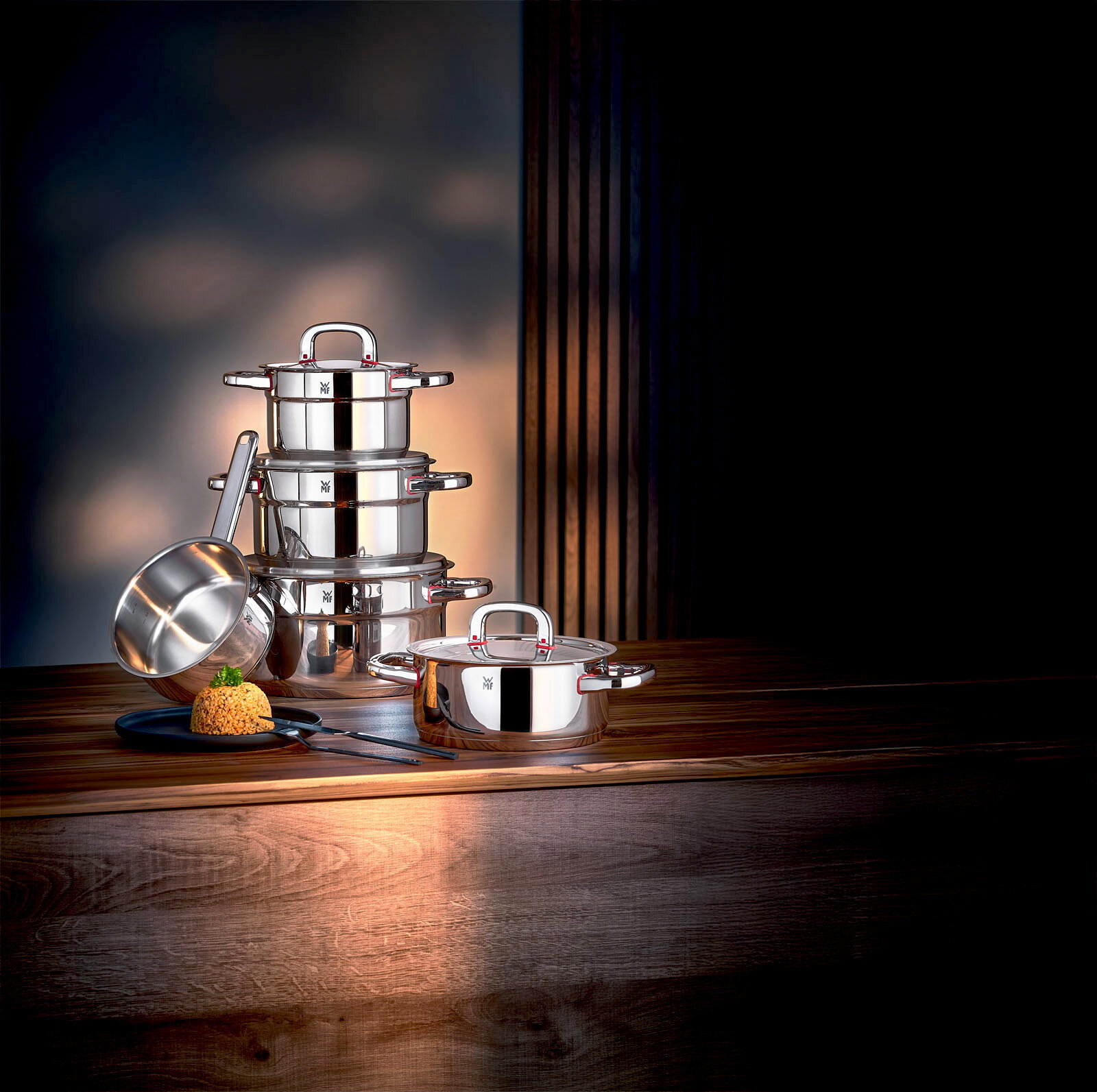 WMF Topfset 3-tlg. ASTORIA Elegantes 3-teiliges Topfset aus Edelstahl, bestehend aus gestapelten Töpfen und einer Stielkasserolle, auf einem Holztisch in seitlicher Perspektive präsentiert.