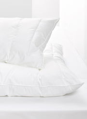 Weißes Kopfkissen auf einem Bett, seitliche Perspektive