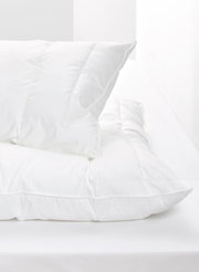 Weißes Kopfkissen auf einem Bett, seitliche Perspektive