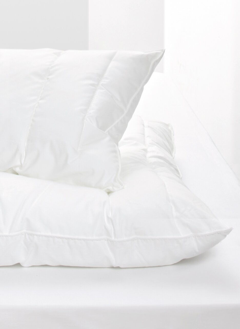 Weißes Kopfkissen auf einem Bett, seitliche Perspektive