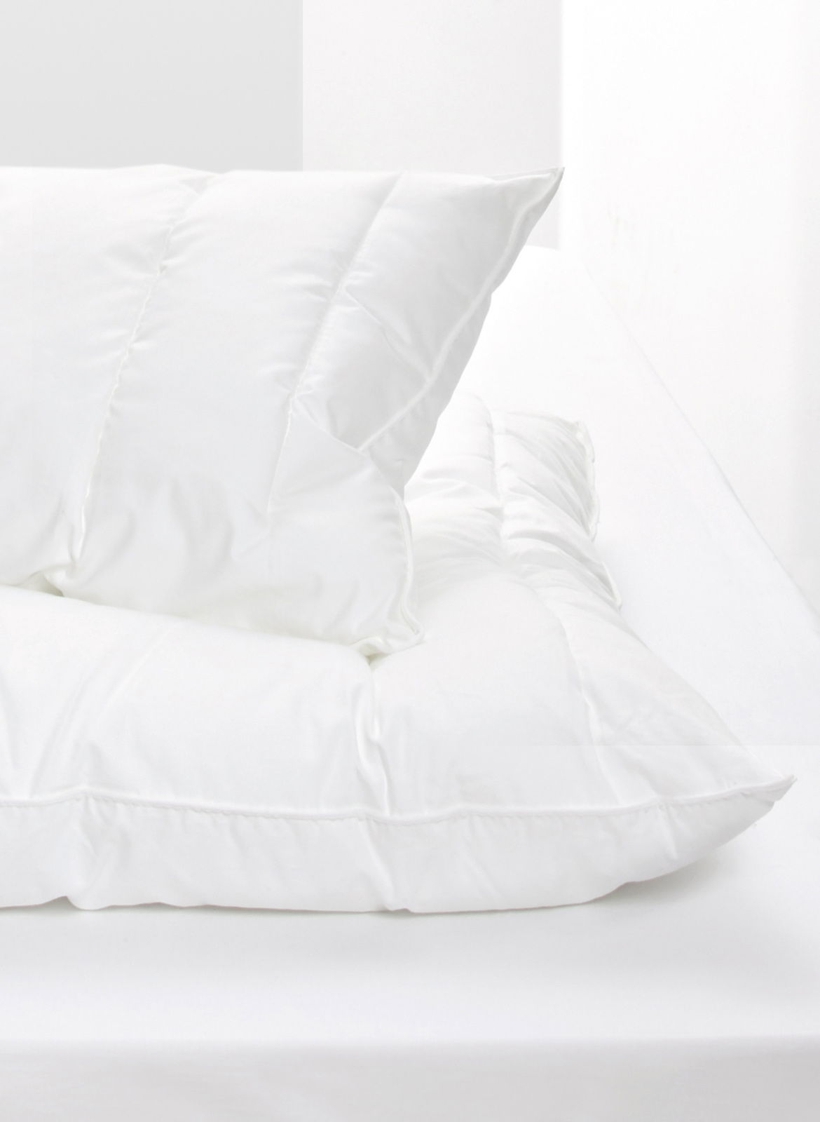 Weißes Kopfkissen auf einem Bett, seitliche Perspektive