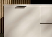 Close-up van een modern, crèmekleurig tv-lowboard met minimalistische handgrepen, gezien vanaf de zijkant
