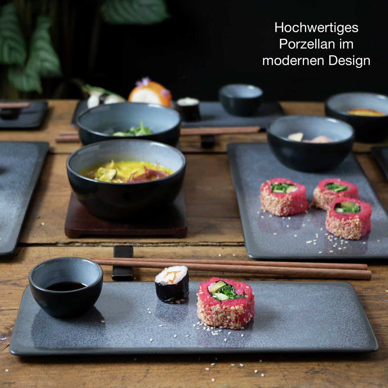 Sushi-Set aus hochwertigem Porzellan in modernem Design, bestehend aus rechteckigen Tellern und Schalen, auf einem Holztisch präsentiert. Perspektive von oben.