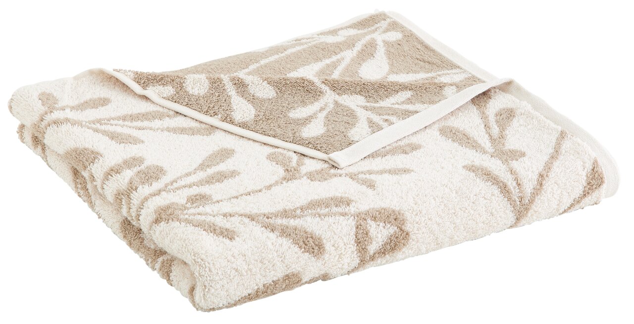 Beigefarbenes Duschtuch mit floralem Muster, gefaltet und aus einer seitlichen Perspektive fotografiert