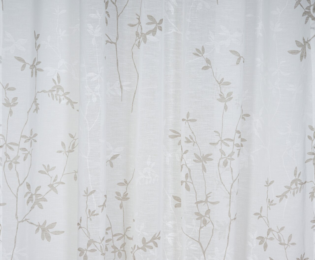 Nahaufnahme eines weißen Vorhangs mit zartem, floralen Muster in Beige, frontal betrachtet.