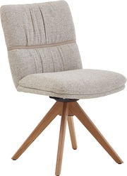 Gepolsterter Esszimmerstuhl mit hellbeigem Stoffbezug, gesteppter Rückenlehne und vierbeinigem Holzgestell, schräg von vorne links fotografiert.