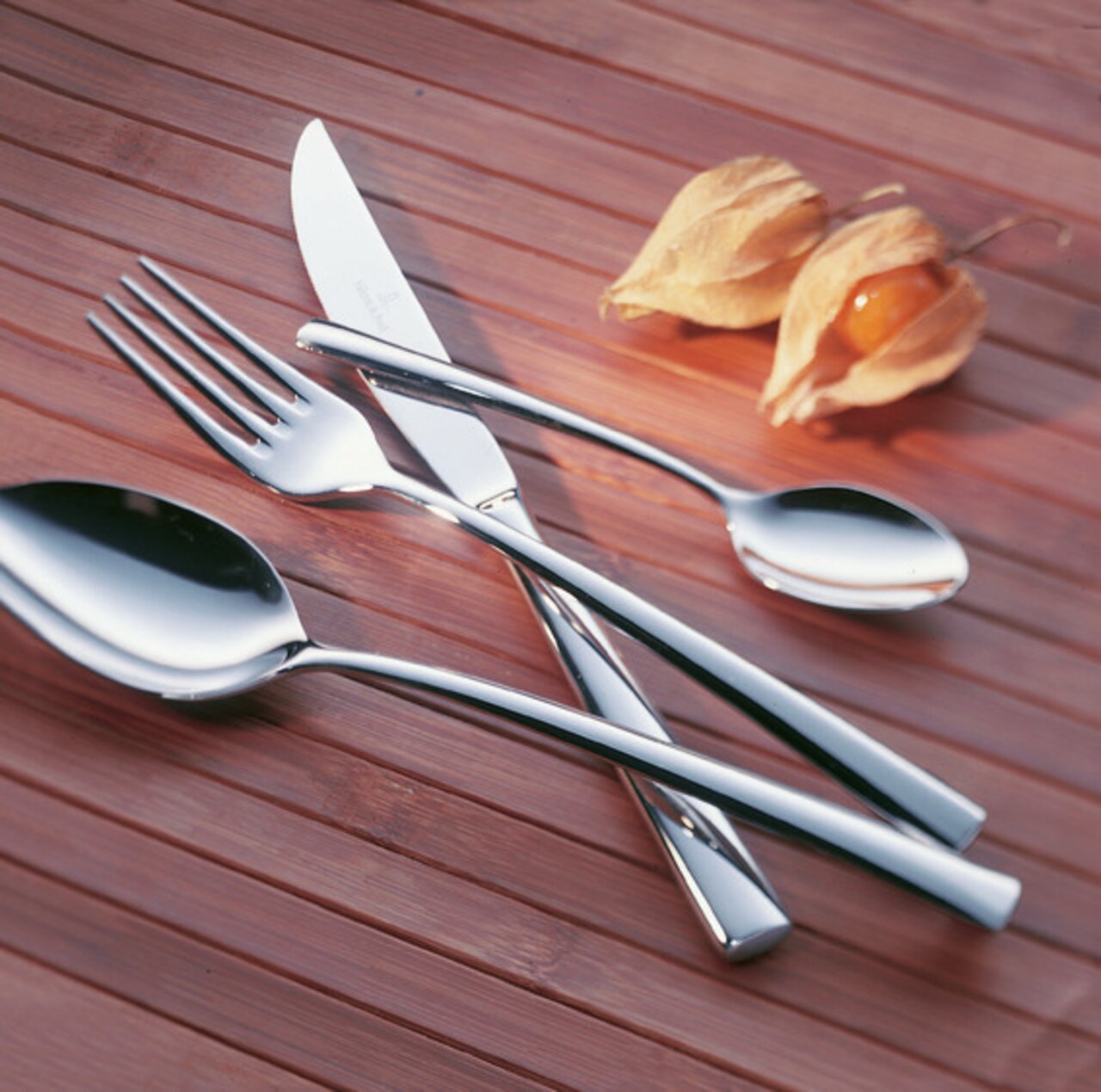 Villeroy & Boch Besteckset 4-tlg. PIEMONT Elegantes Tafelbesteck-Set Piemont, bestehend aus Messer, Gabel, Löffel und Teelöffel, auf Holzuntergrund mit Physalis, aus der Vogelperspektive.