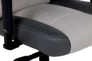 Nahaufnahme eines Gaming-Stuhlsitzes mit grauem Stoff und schwarzem Kunstleder, seitliche Perspektive.