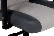 Nahaufnahme eines Gaming-Stuhlsitzes mit grauem Stoff und schwarzem Kunstleder, seitliche Perspektive.